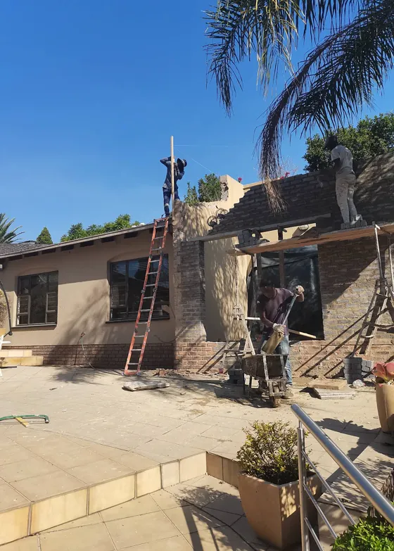 Builders laying brickwork for an extension next to a patio